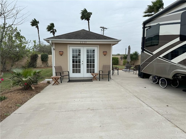 view of outdoor structure with french doors, an outdoor structure, and fence