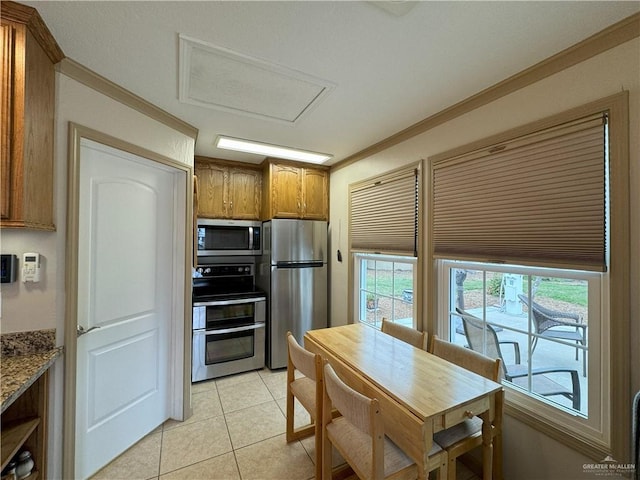 kitchen featuring ornamental molding, brown cabinets, light stone countertops, stainless steel appliances, and light tile patterned flooring