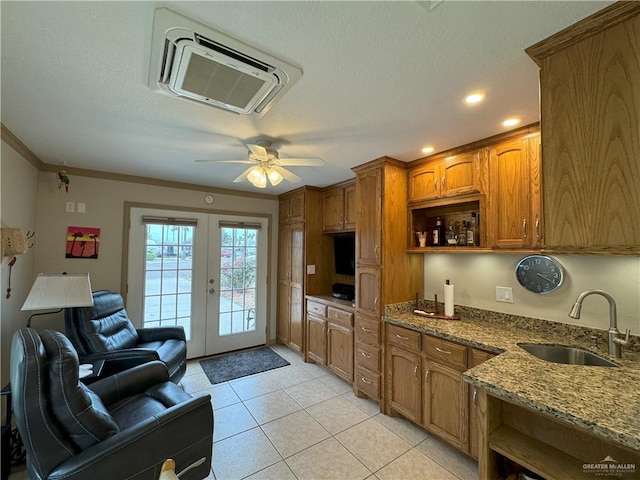 kitchen with french doors, open shelves, brown cabinetry, a sink, and dark stone countertops