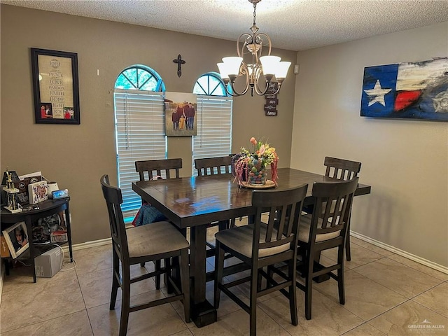 dining space featuring light tile patterned floors, baseboards, a notable chandelier, and a textured ceiling
