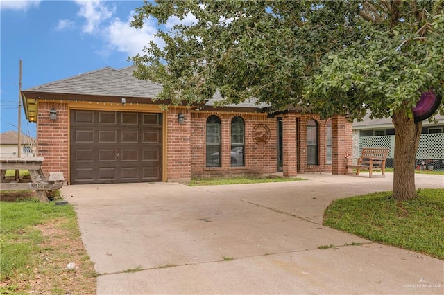 single story home featuring a garage, roof with shingles, brick siding, and driveway
