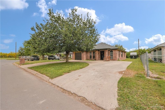 view of front of home with concrete driveway, a front yard, brick siding, a garage, and fence