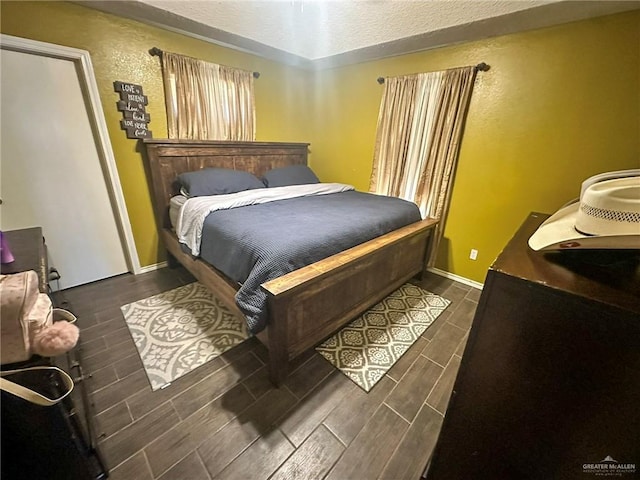 bedroom with a textured wall, baseboards, and wood finish floors