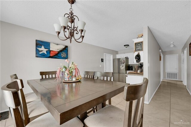 dining area featuring baseboards, an inviting chandelier, light tile patterned floors, a textured ceiling, and visible vents