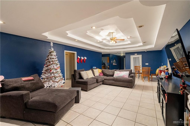 tiled living room with a tray ceiling and ceiling fan