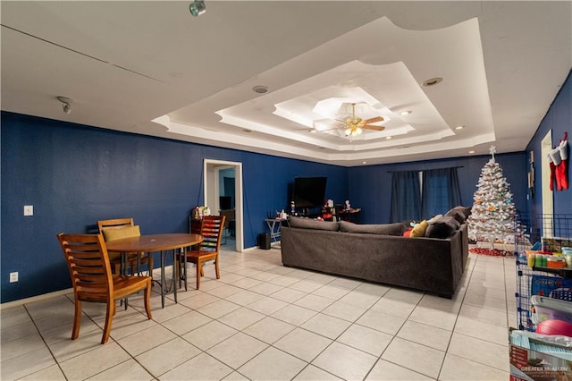 tiled living room featuring ceiling fan and a tray ceiling