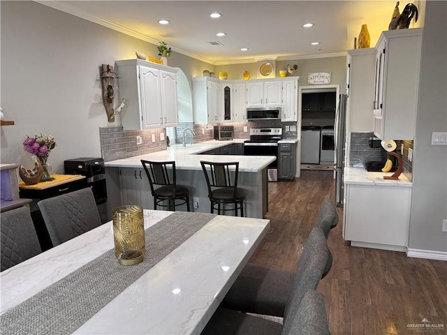 kitchen with a breakfast bar, appliances with stainless steel finishes, dark hardwood / wood-style floors, kitchen peninsula, and white cabinets