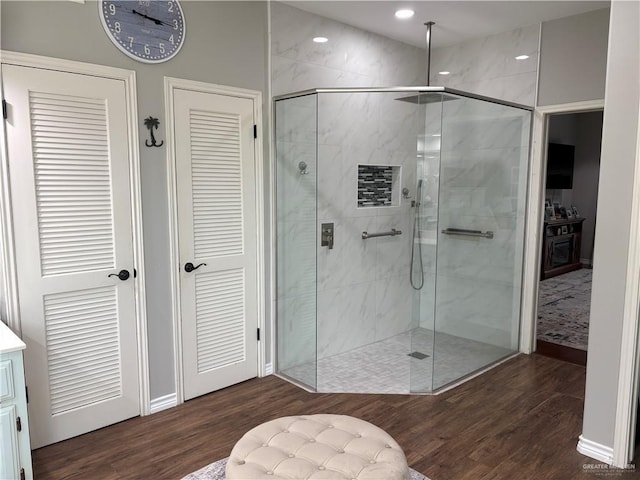 bathroom with a tile shower and wood-type flooring