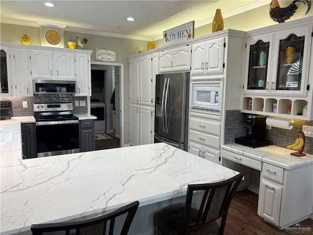 kitchen with appliances with stainless steel finishes, white cabinetry, backsplash, dark hardwood / wood-style floors, and ornamental molding