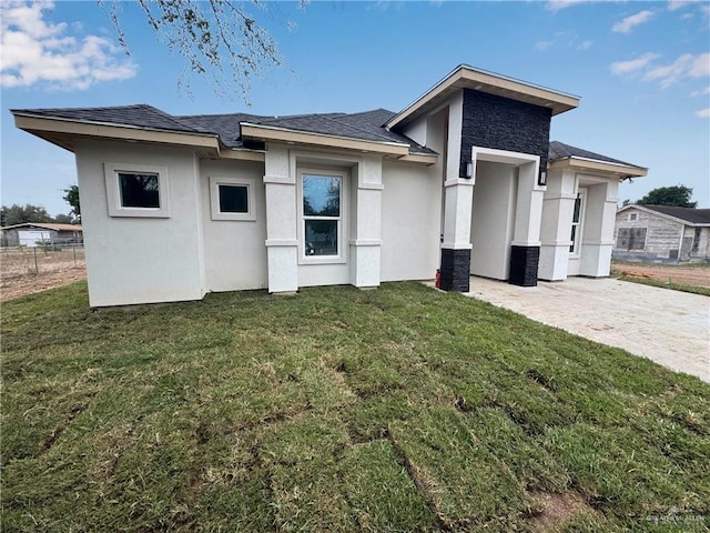 rear view of property featuring a yard, stone siding, and stucco siding