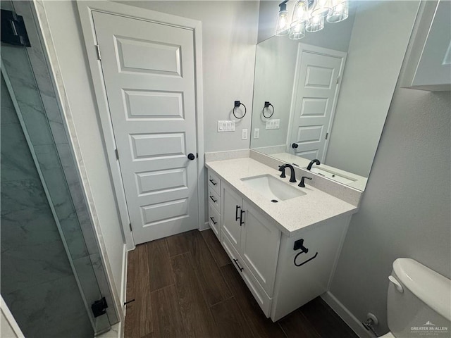 full bath featuring vanity, wood finished floors, baseboards, a stall shower, and toilet