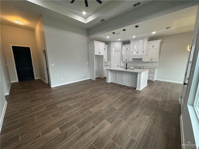 kitchen featuring visible vents, an island with sink, recessed lighting, baseboards, and wood tiled floor