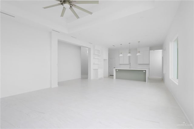 unfurnished living room with ceiling fan and sink