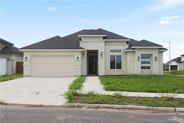 prairie-style home featuring a garage and a front lawn