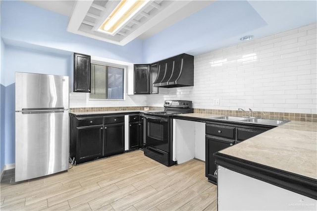 kitchen featuring black range with electric stovetop, decorative backsplash, freestanding refrigerator, dark cabinets, and wall chimney exhaust hood