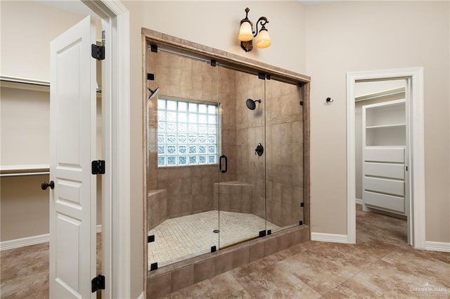 bathroom featuring a shower stall, a spacious closet, baseboards, and tile patterned flooring