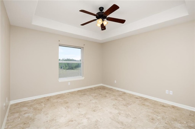 spare room featuring baseboards, a raised ceiling, and a ceiling fan