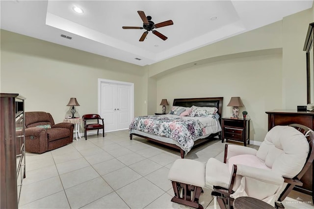 bedroom featuring a raised ceiling, ceiling fan, and light tile patterned floors