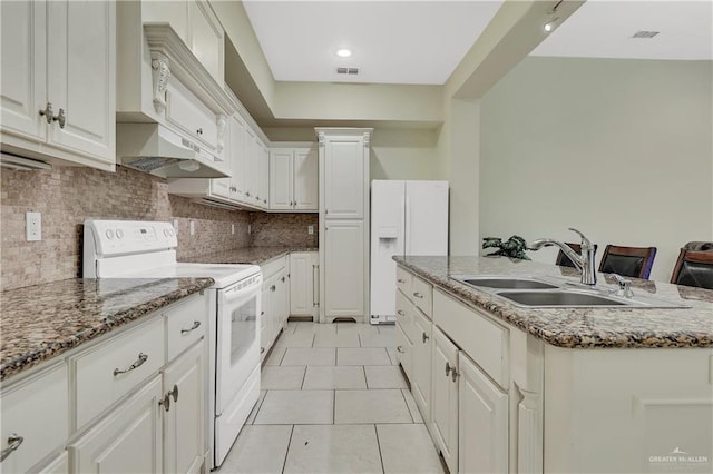 kitchen with sink, light tile patterned floors, an island with sink, white appliances, and white cabinets