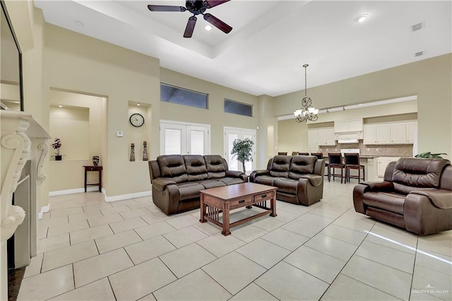 tiled living room featuring ceiling fan with notable chandelier and a high ceiling