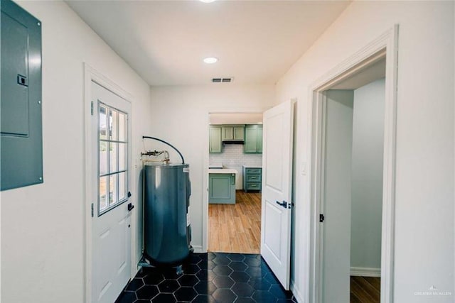 hallway featuring electric panel, dark wood-type flooring, and water heater