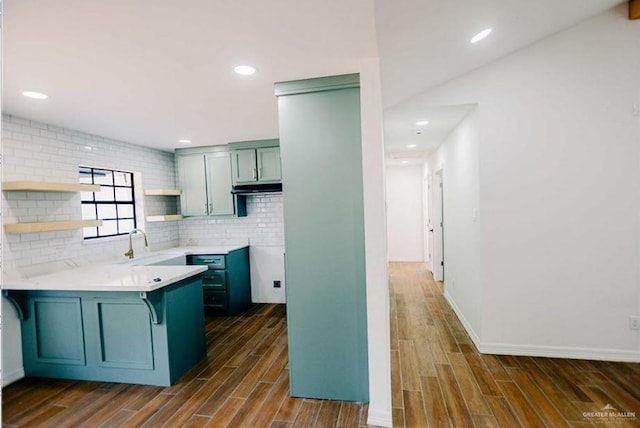 kitchen with kitchen peninsula, a breakfast bar, dark hardwood / wood-style floors, and sink