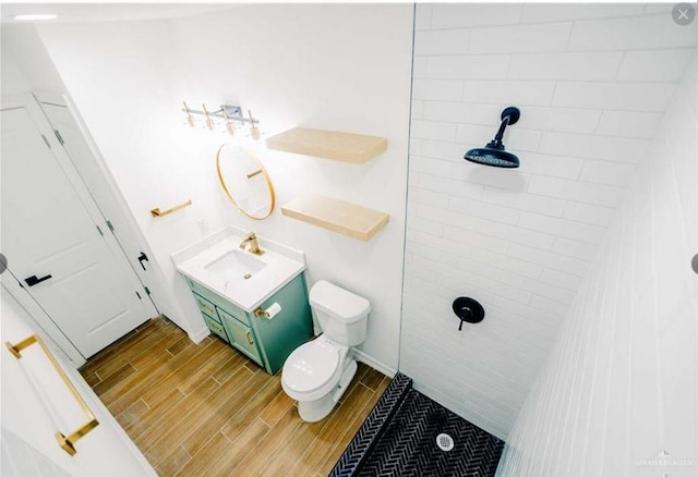 bathroom featuring tiled shower, vanity, and toilet