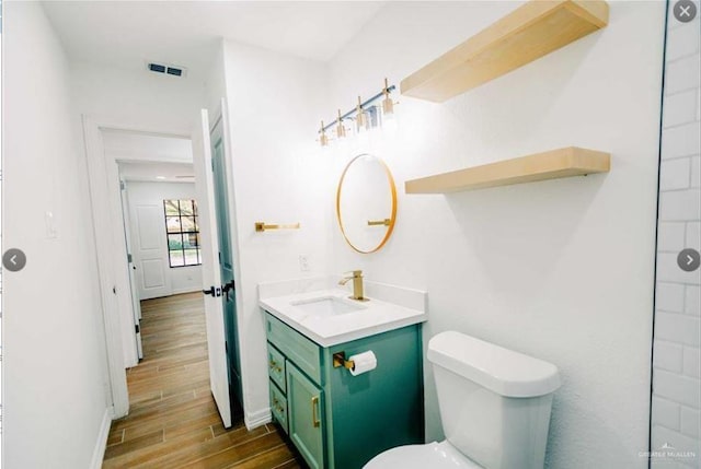 bathroom with toilet, vanity, and hardwood / wood-style flooring