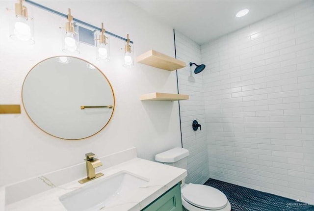 bathroom with tiled shower, vanity, and toilet