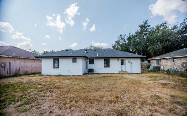 rear view of property featuring a lawn and cooling unit