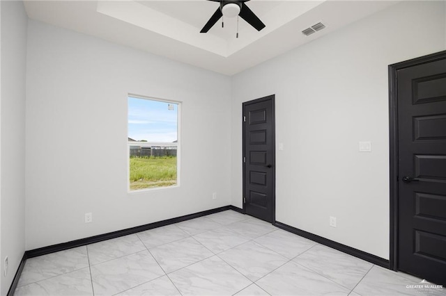 spare room featuring ceiling fan and a raised ceiling