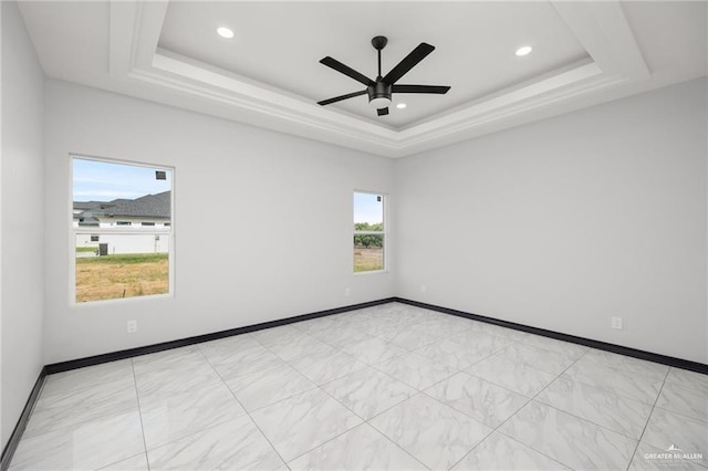 empty room with a raised ceiling and ceiling fan