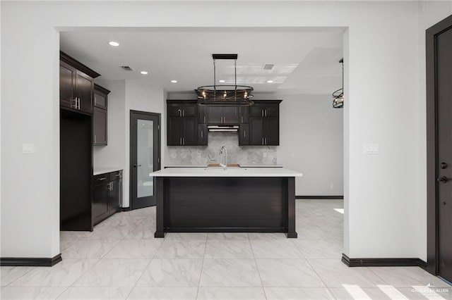 kitchen with sink, a kitchen island with sink, and decorative backsplash