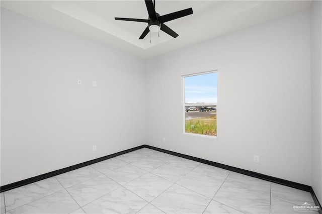 spare room with ceiling fan and a raised ceiling