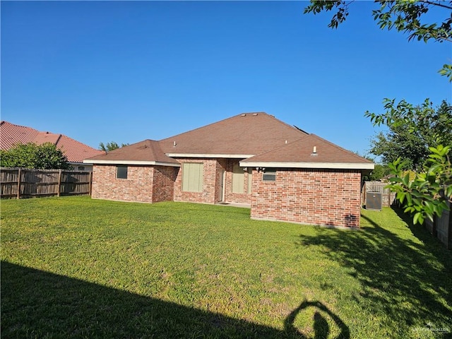 rear view of property with brick siding, a fenced backyard, and a yard