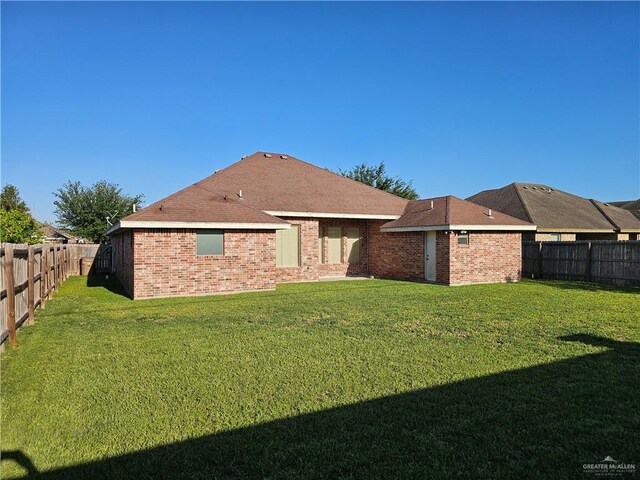 back of house with a lawn, brick siding, and a fenced backyard