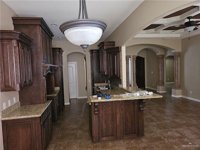 kitchen featuring arched walkways, a ceiling fan, decorative columns, and coffered ceiling