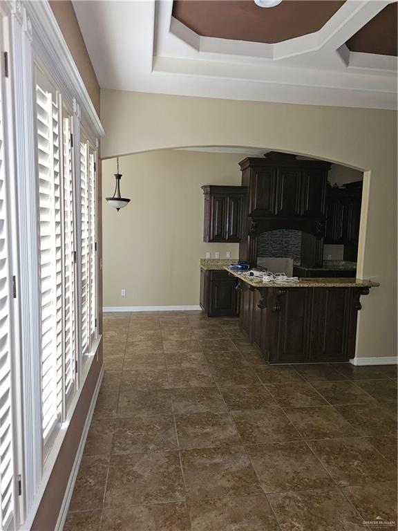 kitchen featuring baseboards and a raised ceiling