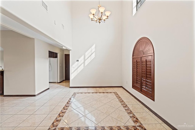 foyer with a notable chandelier, light tile patterned floors, visible vents, and baseboards