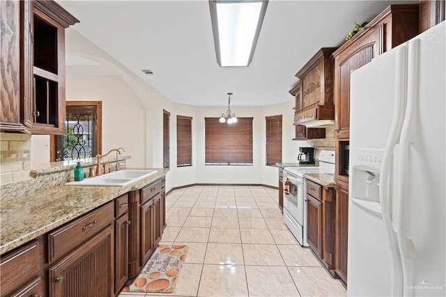 kitchen featuring white appliances, a sink, visible vents, backsplash, and decorative light fixtures