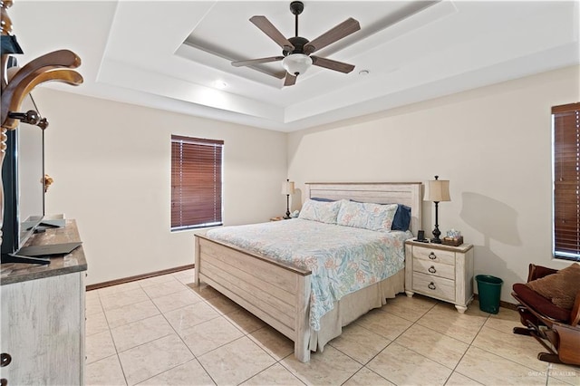 bedroom with light tile patterned flooring, a raised ceiling, a ceiling fan, and baseboards