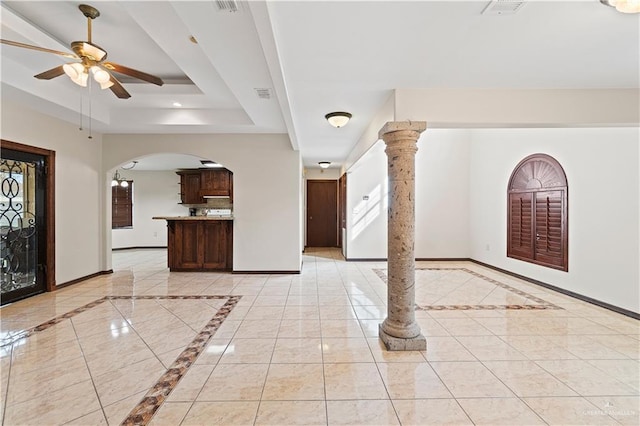 entrance foyer with arched walkways, a ceiling fan, visible vents, baseboards, and a raised ceiling