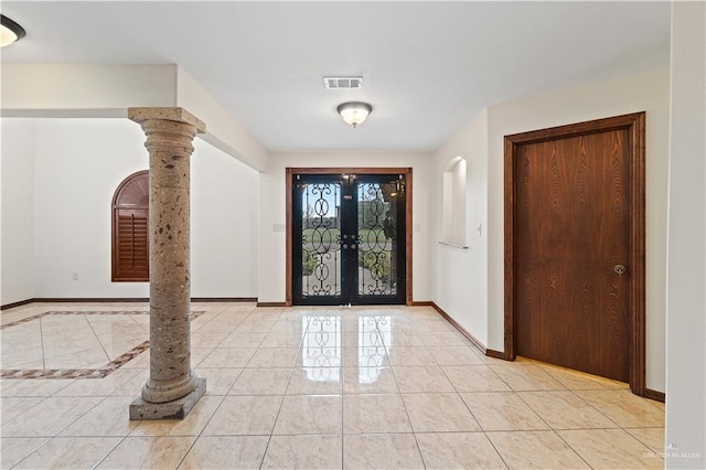 foyer featuring arched walkways, light tile patterned floors, visible vents, baseboards, and ornate columns