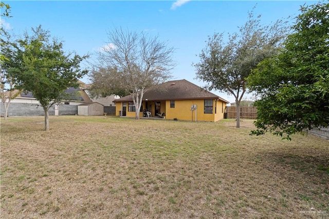 view of yard featuring a storage shed, a fenced backyard, and an outbuilding