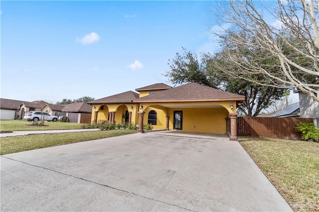 mediterranean / spanish-style home with driveway, a front lawn, fence, and stucco siding