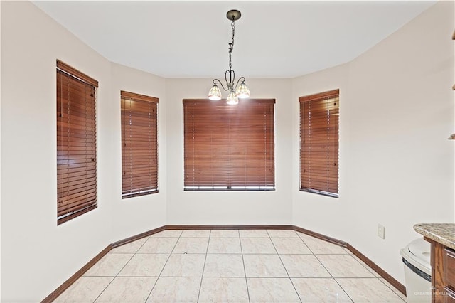 unfurnished dining area featuring a chandelier, light tile patterned flooring, and baseboards