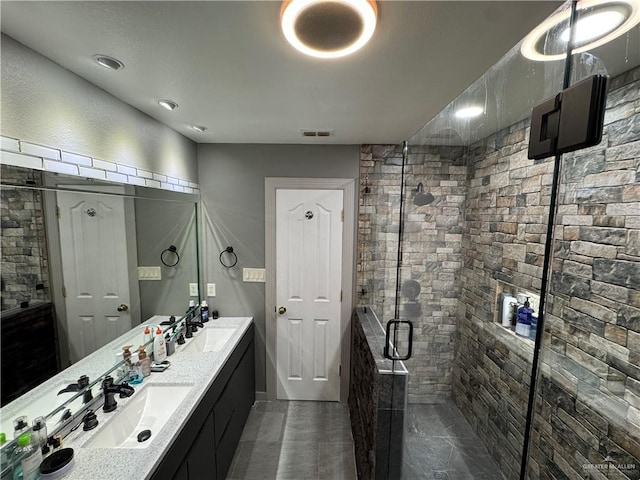 bathroom featuring double vanity, a stall shower, visible vents, and a sink