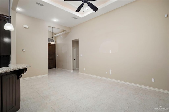 unfurnished living room with ceiling fan and a raised ceiling