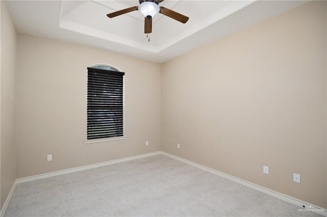 spare room featuring ceiling fan and a raised ceiling