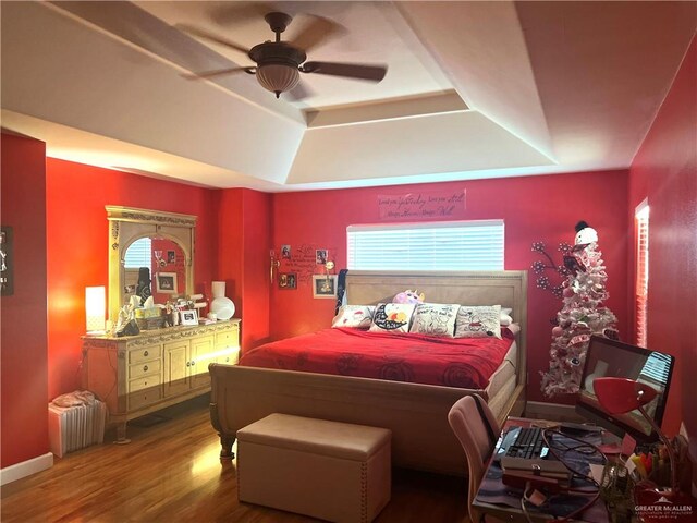 bedroom with a raised ceiling, radiator, ceiling fan, and hardwood / wood-style flooring